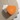 An orange, heart-shaped box with a Venchi logo sits on a textured beige cloth next to a floral-patterned card and envelope that reads Best wishes.
